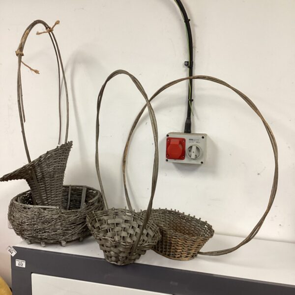 Four vintage wicker baskets displayed against a white wall.