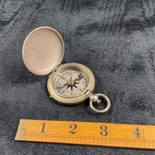Vintage WW2 US Witnauer compass, closed, on dark surface.