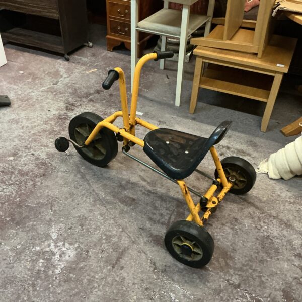 Vintage yellow child’s tricycle with metal wheels.