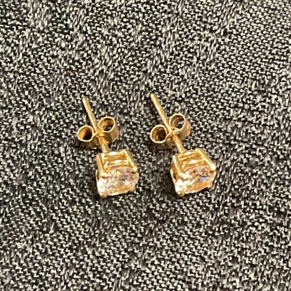 Close-up of 9 carat gold stud earrings with white stones.