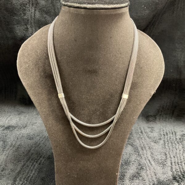 Close-up of 925 silver triple chain necklace on display.