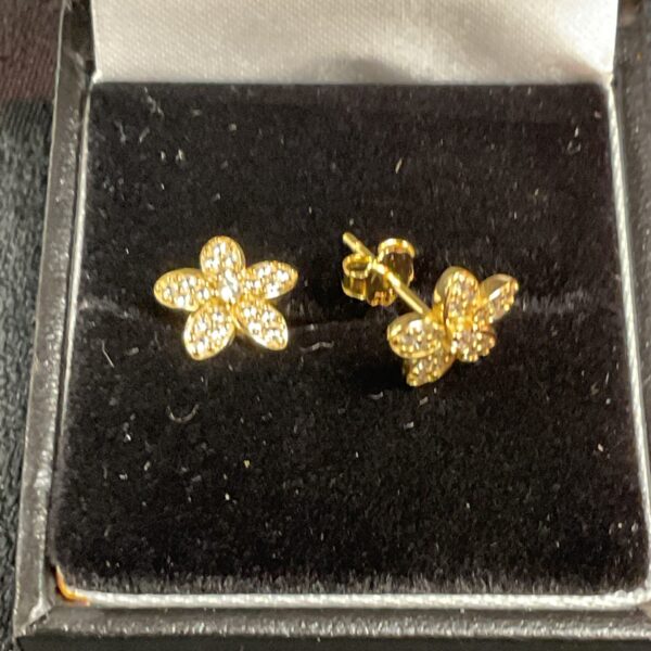 Close-up of 9ct gold daisy stud earrings with sparkling stones.