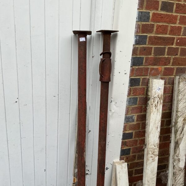 Two rusty metal acro props for construction and scaffolding.