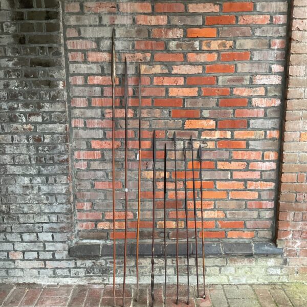 Group of six vintage African tribal spears against a brick wall.