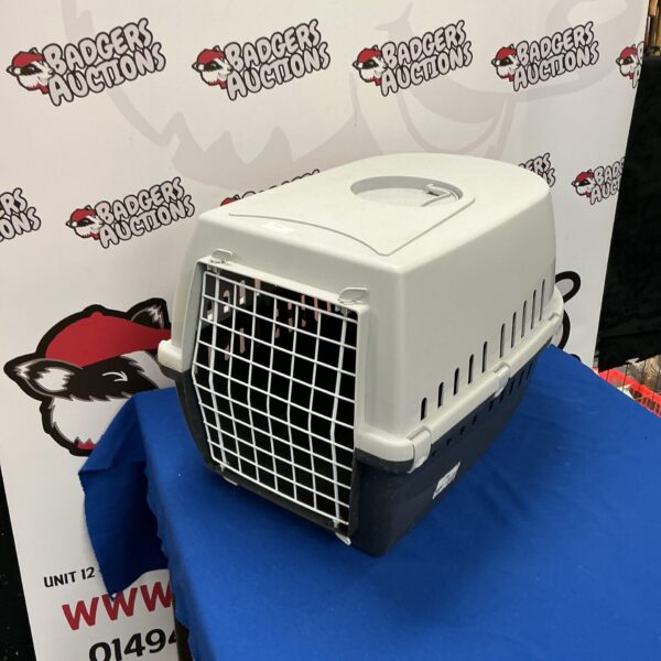 White plastic animal transport cage with wire front.