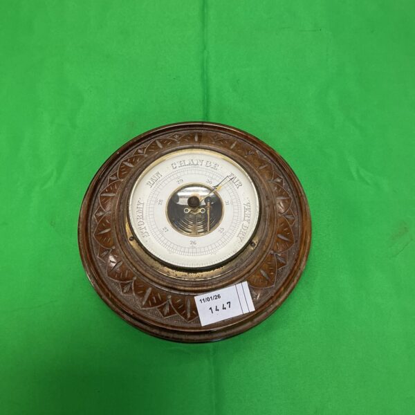 Antique carved wood barometer for measuring weather conditions.