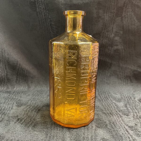 Antique amber glass bitters bottle with embossed lettering.