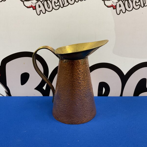 Antique copper jug with brass handle and hammered texture.