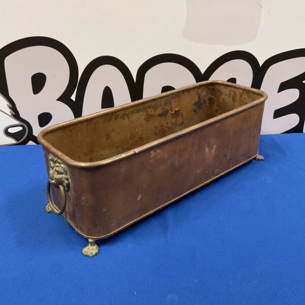 Antique copper trough with lion head handles and claw feet.