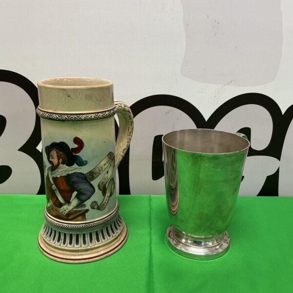 Antique German beer stein and Marlborough silver plate tankard on display.