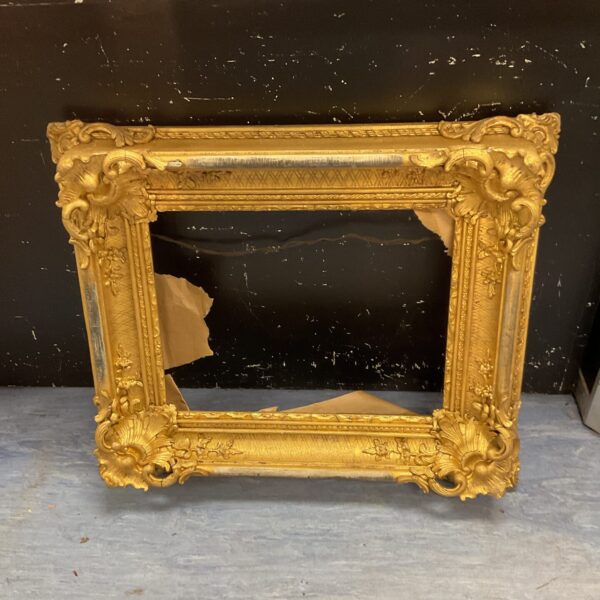 Ornate antique gilded picture frame with intricate carvings.