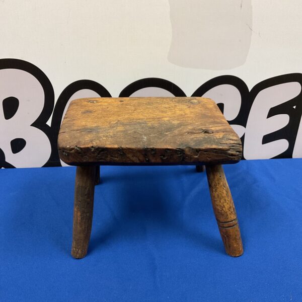 Antique oak gout stool with three legs, rustic vintage style.