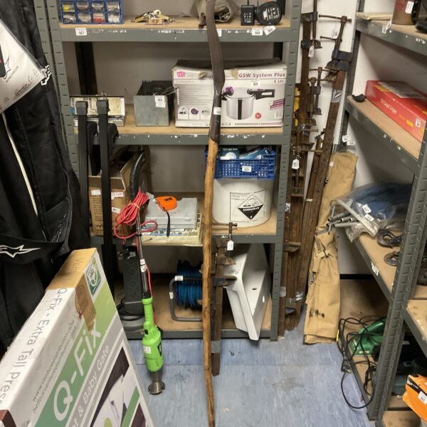 Antique scythe with a weathered wooden pole and curved blade.