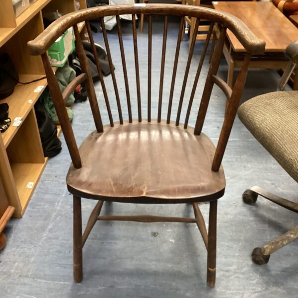 Antique stick back chair with wooden construction and curved arms.