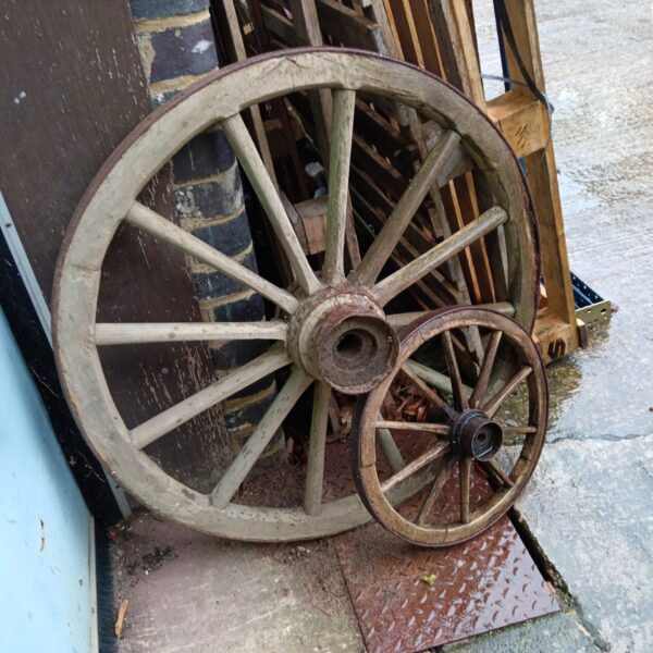 Antique wooden cart wheel with iron banding, vintage farm equipment.