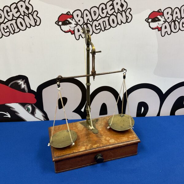 Vintage apothecary balance scales with brass pans and wooden base.