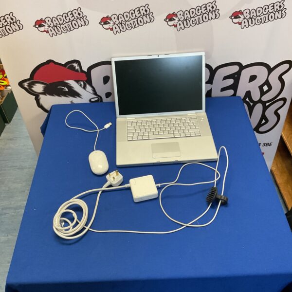 Vintage Apple MacBook Pro A1260 laptop with charger and mouse.