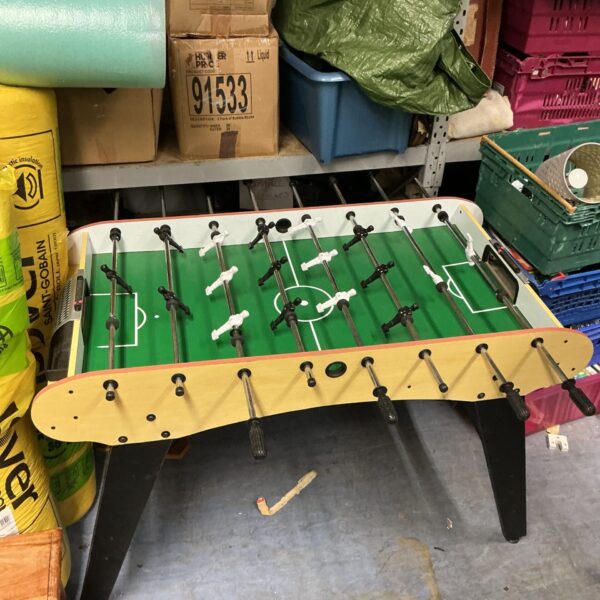 Green full size bar football table in a room.