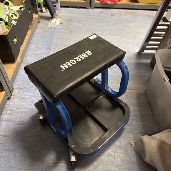 Blue Bergen mechanics stool on wheels in a workshop setting.