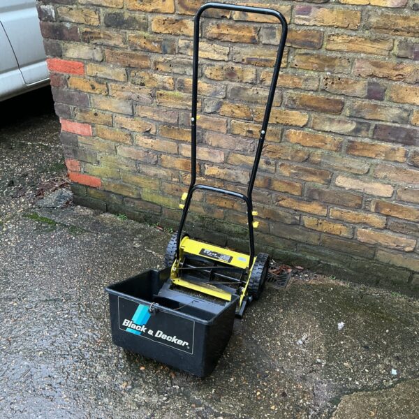 Vintage Black and Decker push lawnmower in a garden setting.