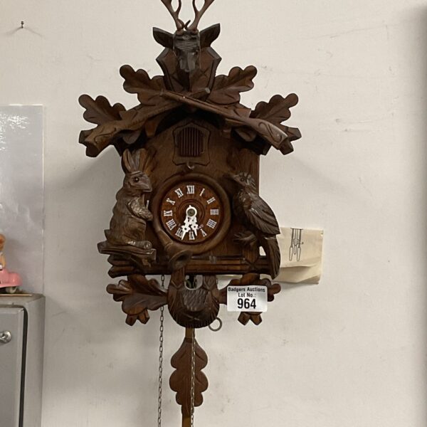 Vintage Black Forest cuckoo clock with detailed hunting scene carving.