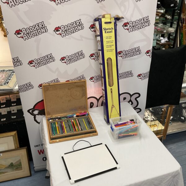 Artist easel set with pens and pencils on a table.