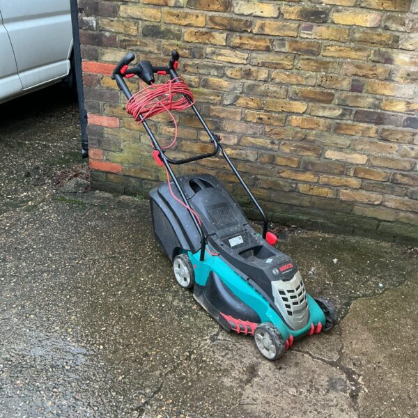 Side view of a Bosch electric lawnmower in a garden setting.