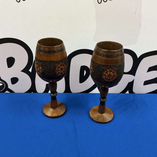 Two intricately carved wooden goblets with detailed designs.