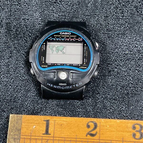 Close-up of vintage Casio digital thermometer watch with black strap.