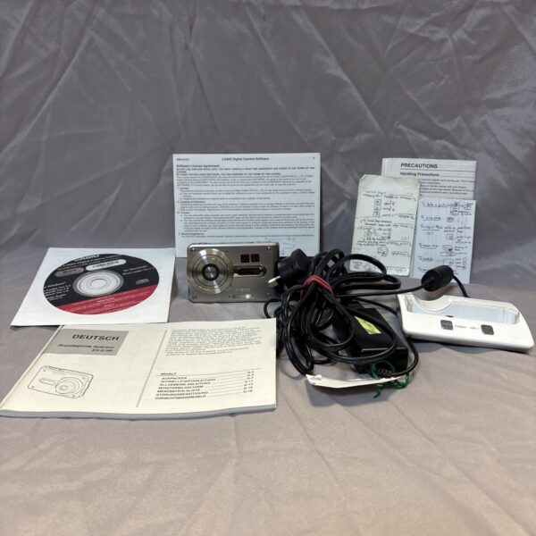 Vintage Casio Exilim EX-S100 digital camera with charger and papers.