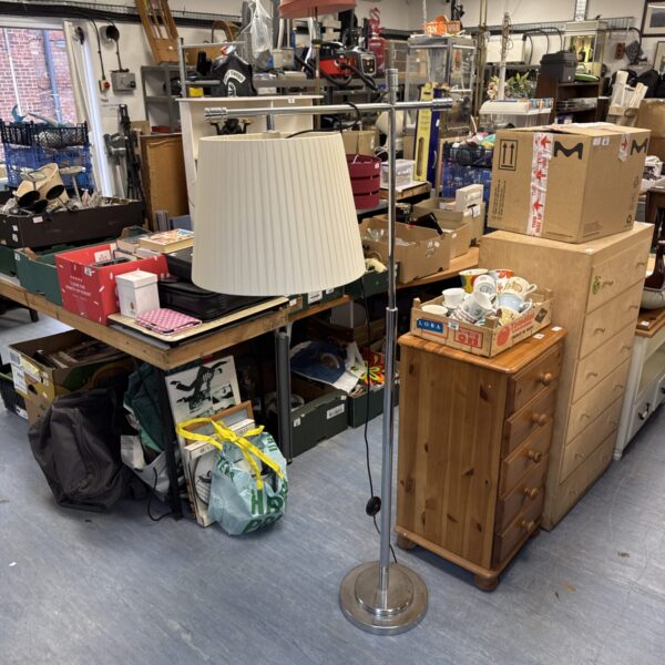 Vintage chrome floor lamp with pleated shade in a cluttered room.