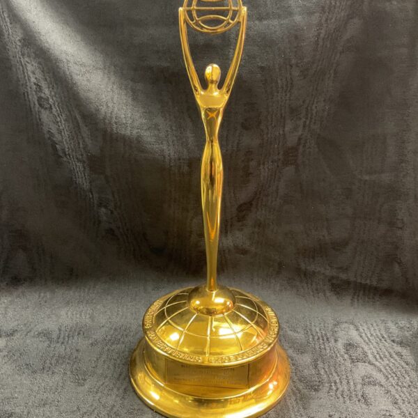Front view of a vintage brass Clio Award trophy.