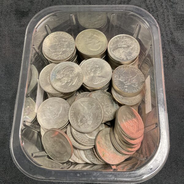 Assorted commemorative coins including Charles and Diana coins in a plastic container.