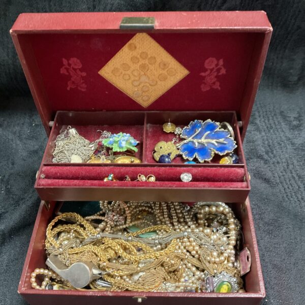 Red lined jewellery box filled with vintage costume jewellery.