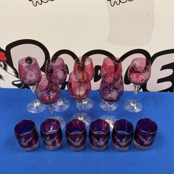 Vintage cranberry glass wine and whiskey glasses with etched designs.