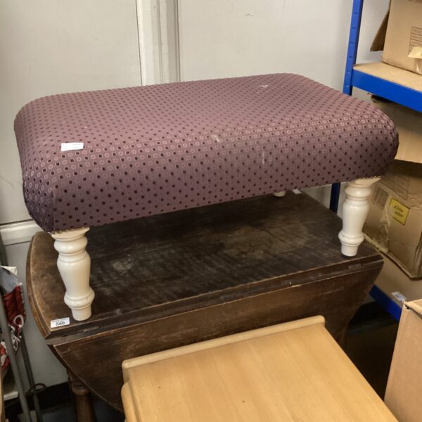 Patterned cushioned footstool with turned wooden legs.