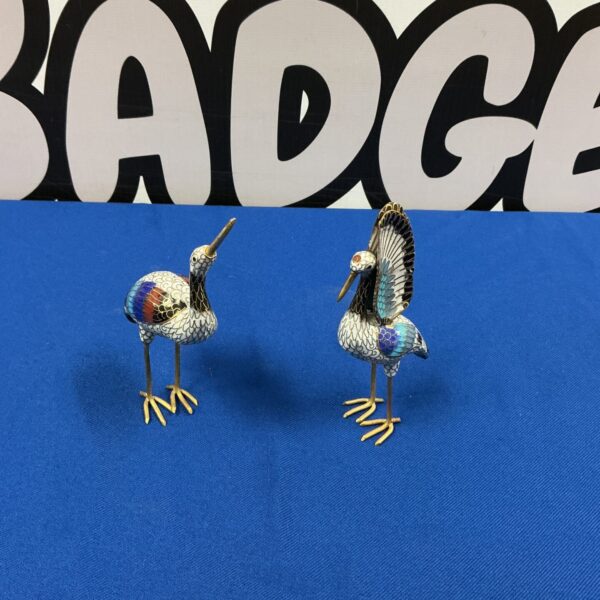 Pair of vintage decorative bird figurines on blue background.