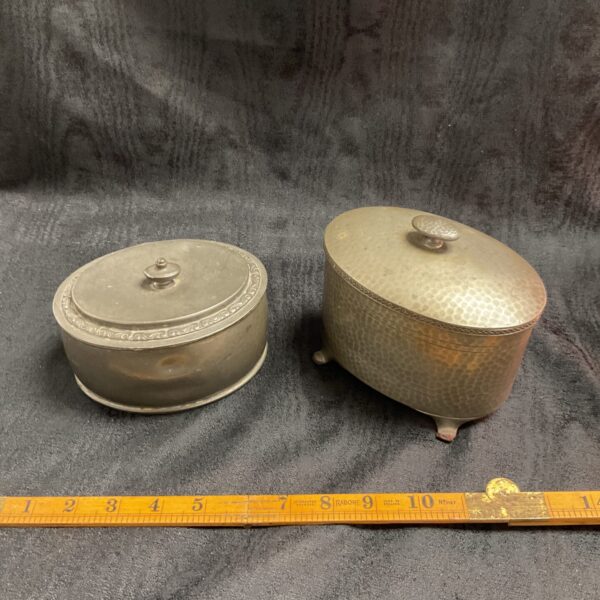 Antique pair of English pewter lidded pots on wooden surface.