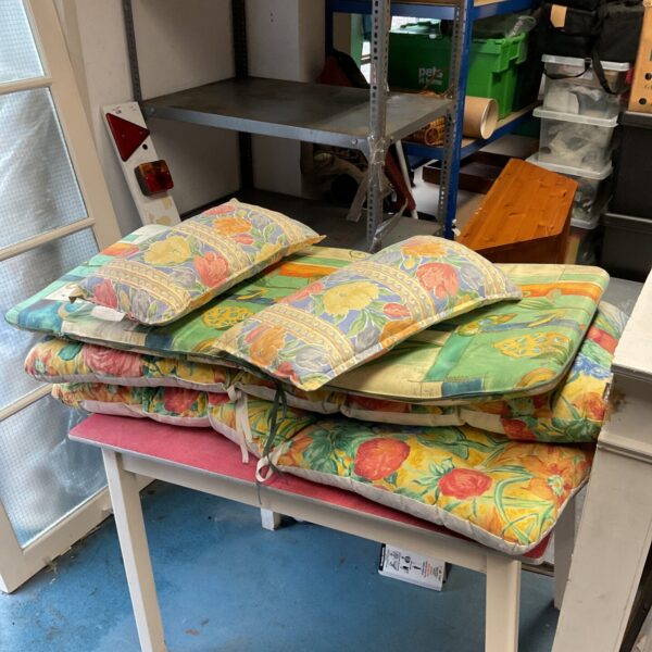 Three floral garden lounger cushions stacked on a table.