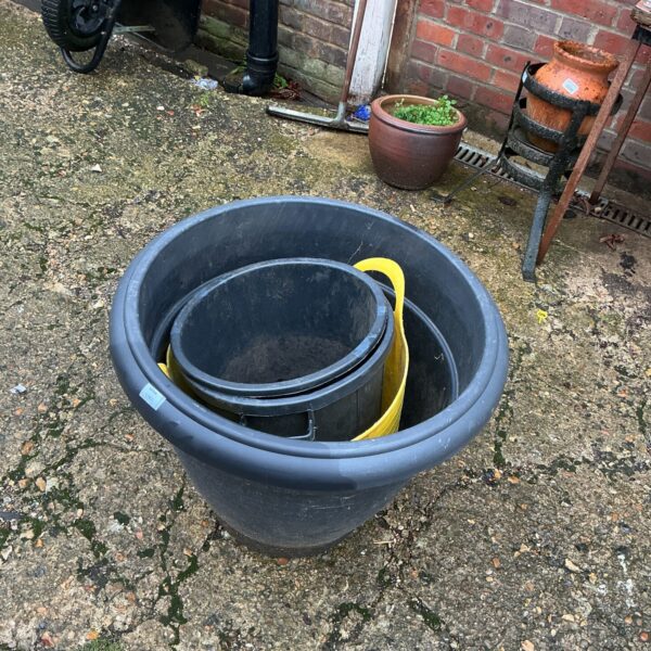 Dark grey plastic garden planters nested together for gardening.