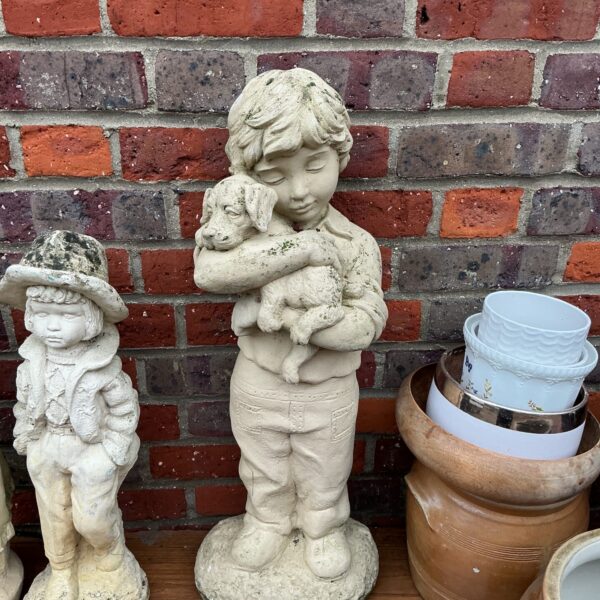 Vintage concrete garden statue of boy with dog.