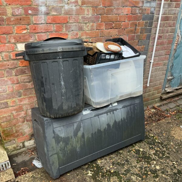 Large plastic garden storage box with other containers outdoors.