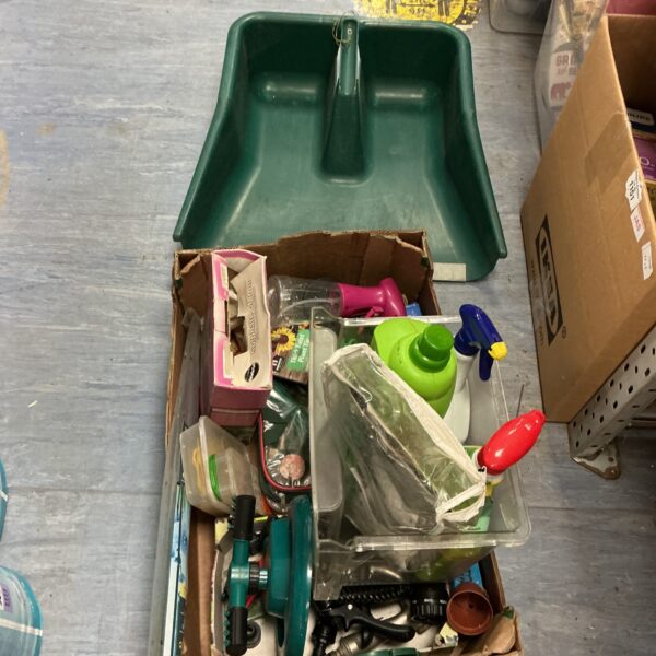 A lot of used gardening equipment including a large green leaf shovel.