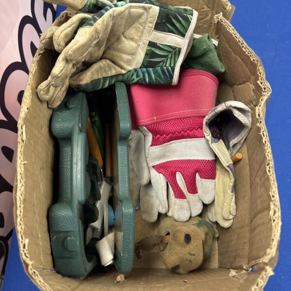Assorted gardening tools including shears and gloves in a box.