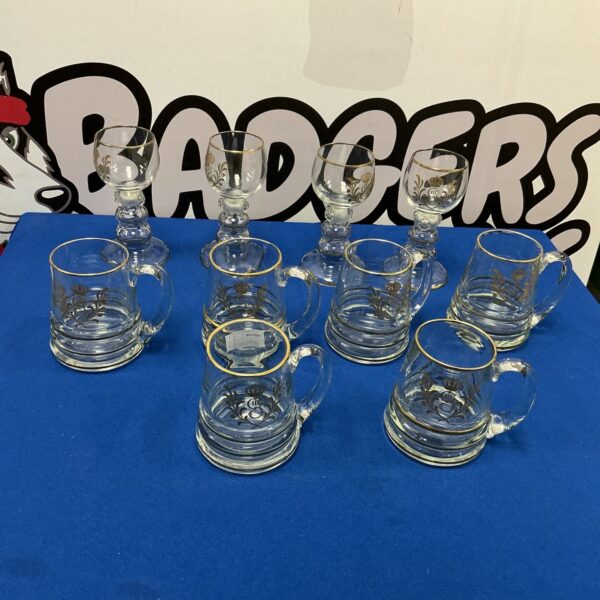 Antique George III tankards and goblets with gold leaf rims on display.