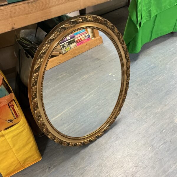 Ornate gold gilt framed oval mirror for wall decoration.