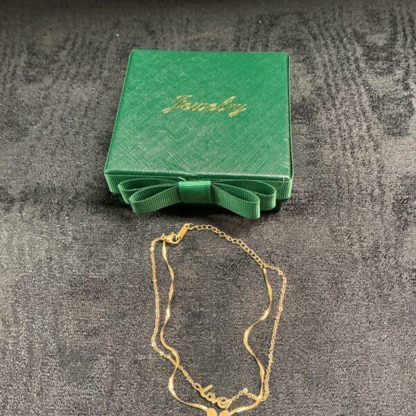 Gold heart anklet presented in a green gift box.
