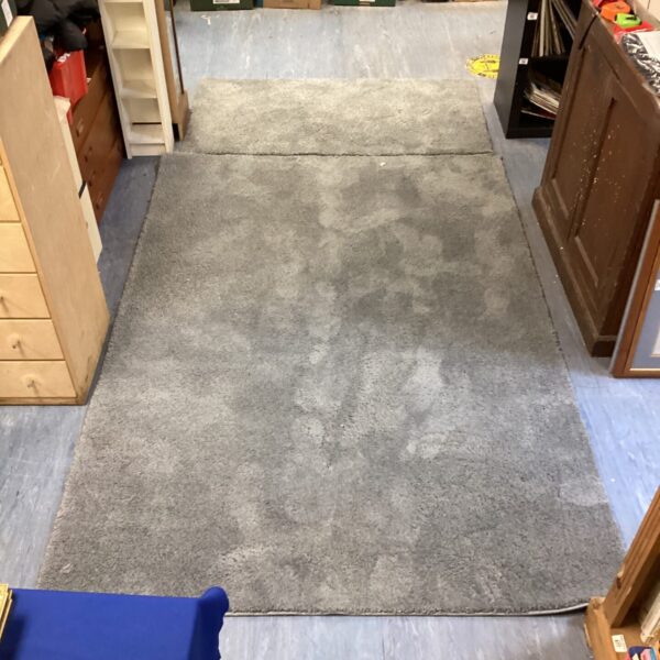 Two grey Tesco rugs, a runner and a larger rug, on a floor.