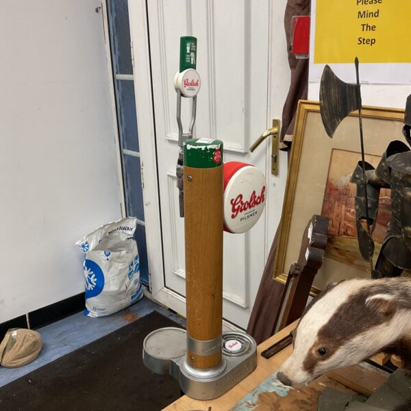 Vintage Grolsch beer pump in front of a door.