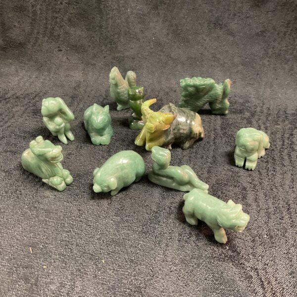 Collection of miniature jade animal carvings on a dark surface.